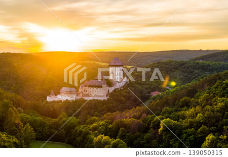 Aerial view of beautiful sunset over the Karlstejn castle, Czech Republic. Drone shot of ancient castle with near forest. Castle in gothic style was build by emperor of Rome rise, Charles IV. Aerial view of beautiful sunset over the Karlstejn castle, Czech Republic. Drone shot of ancient castle with near forest. Castle in gothic style was build by emperor of Rome rise, Charles IV. 139050315