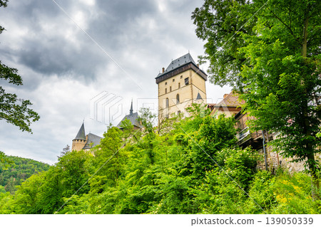 Famous medieval gothic castle Karlstejn on top of the hill. Beautiful stronghold is built by king Charles IV. Historical national heritage of Czech Republic is placed near Prague city. Cloudy weather Famous medieval gothic castle Karlstejn on top of the hill. Beautiful stronghold is built by king Charles IV. Historical national heritage of Czech Republic is placed near Prague city. Cloudy weather 139050339