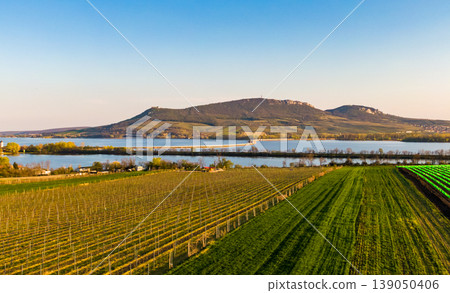 Panoramic aerial view of Palava hills, czech republic. Vineyard land near water reservoir Nove mlyny. Concept of agriculture and wine production. Summer weather, vibrant colors at sunset time. Panoramic aerial view of Palava hills, czech republic. Vineyard land near water reservoir Nove mlyny. Concept of agriculture and wine production. Summer weather, vibrant colors at sunset time. 139050406