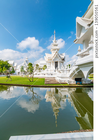 The white temple (Wat Rong Khun) in Chiang Rai city, Thailand. Beautiful buddhist ancient building with bridge above damned souls of sinners, path to the heaven. Famous tourist destination. Blue sky 139050561