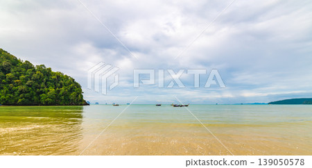 Beautiful beach at Ao Nang, Krabi Thailand. View of pure blue water with long tailed boats prepared for passengers. Cloudy weather, tropical climate. Famous vacation tourist destination Beautiful beach at Ao Nang, Krabi Thailand. View of pure blue water with long tailed boats prepared for passengers. Cloudy weather, tropical climate. Famous vacation tourist destination 139050578