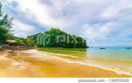 Beautiful beach at Ao Nang, Krabi Thailand. View of pure blue water with long tailed boats prepared for passengers. Cloudy weather, tropical climate. Famous vacation tourist destination Beautiful beach at Ao Nang, Krabi Thailand. View of pure blue water with long tailed boats prepared for passengers. Cloudy weather, tropical climate. Famous vacation tourist destination 139050580