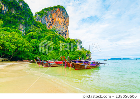 The famous Railay beach at Krabi, Thailand. Long tailed boats are prepared for passengers near limestone rock. Tropical paradise, famous tourist destination. Turquoise sea with white sand The famous Railay beach at Krabi, Thailand. Long tailed boats are prepared for passengers near limestone rock. Tropical paradise, famous tourist destination. Turquoise sea with white sand 139050600