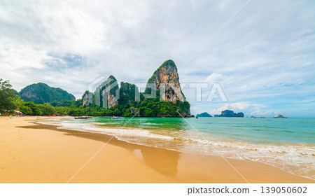 Panoramic view of famous Railay beach, Krabi Thailand. Big limestone rock above pure turquoise sea with boats for tourists. Tropical paradise at Andaman sea with white sand. Vibrant colors Panoramic view of famous Railay beach, Krabi Thailand. Big limestone rock above pure turquoise sea with boats for tourists. Tropical paradise at Andaman sea with white sand. Vibrant colors 139050602