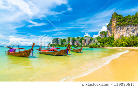 Beautiful view of long tail boats on water in Railay beach bay, Thailand, Krabi town. Famous tourist destination for vacation in tropical paradise. Beautiful summer day. Big limestone hill and rock 139050615