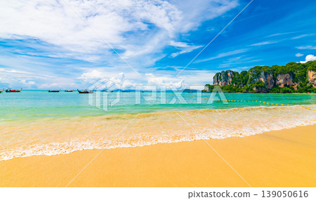 Beautiful view of long tail boats on water in Railay beach bay, Thailand, Krabi town. Famous tourist destination for vacation in tropical paradise. Beautiful summer day. Big limestone hill and rock 139050616