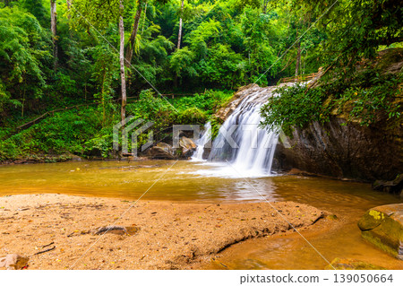 Beautiful waterfall Mae Sa, Thailand. Fresh and pure water stream is flowing on the rock stone ground in tropical rainforest. Fresh plants and trees above river. Vibrant colors in pure nature Beautiful waterfall Mae Sa, Thailand. Fresh and pure water stream is flowing on the rock stone ground in tropical rainforest. Fresh plants and trees above river. Vibrant colors in pure nature 139050664