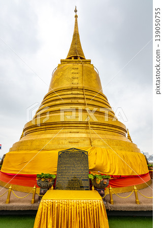 Wat Saket temple with golden stupa and angel statue. Symbol of buddhism in Bangkok city, Thailand. Majestic and religion symbol of Thai culture. Cloudy weather Wat Saket temple with golden stupa and angel statue. Symbol of buddhism in Bangkok city, Thailand. Majestic and religion symbol of Thai culture. Cloudy weather 139050755