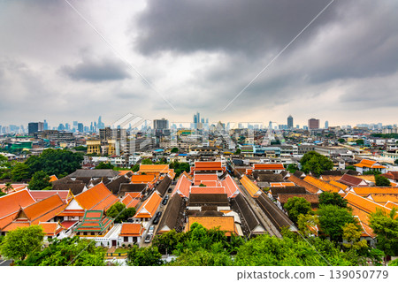 Panorama view of Bangkok city, Thailand. Cityscape of residental buildings in foreground, temples, skyscrapers and modern buildings in far. Fresh trees and plants. Cloudy weather, dramatic clouds. Panorama view of Bangkok city, Thailand. Cityscape of residental buildings in foreground, temples, skyscrapers and modern buildings in far. Fresh trees and plants. Cloudy weather, dramatic clouds. 139050779