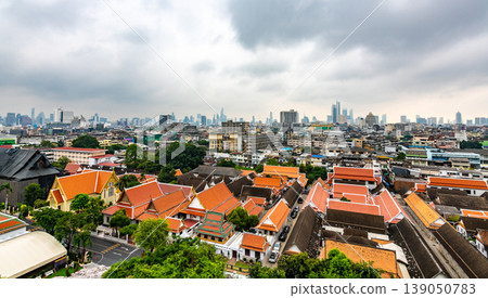 Panorama view of Bangkok city, Thailand. Cityscape of residental buildings in foreground, temples, skyscrapers and modern buildings in far. Fresh trees and plants. Cloudy weather, dramatic clouds. Panorama view of Bangkok city, Thailand. Cityscape of residental buildings in foreground, temples, skyscrapers and modern buildings in far. Fresh trees and plants. Cloudy weather, dramatic clouds. 139050783