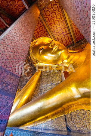 Beautiful statue of reclining golden Buddha placed in Wat Pho temple, Bangkok. Spiritual place of buddhism religion with beautiful ornaments on the pillar. Detail view of Buddha's head Beautiful statue of reclining golden Buddha placed in Wat Pho temple, Bangkok. Spiritual place of buddhism religion with beautiful ornaments on the pillar. Detail view of Buddha's head 139050820