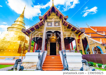 Wat Phra Singh temple in Chiang Mai city, Thailand. Wooden building is ancient place of buddhist spirituality in northen Thailand. Near is golden chedi stupa and pagoda. Famous tourist destination Wat Phra Singh temple in Chiang Mai city, Thailand. Wooden building is ancient place of buddhist spirituality in northen Thailand. Near is golden chedi stupa and pagoda. Famous tourist destination 139050825