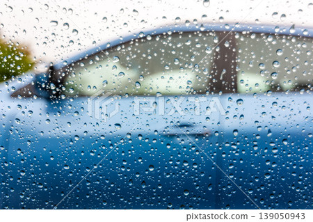 Water drops on the car window. View from car with raindrops on the window to next car with blue color. Rainy day Water drops on the car window. View from car with raindrops on the window to next car with blue color. Rainy day 139050943