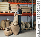 Young male warehouse worker managing bags with coffee beans 139051144