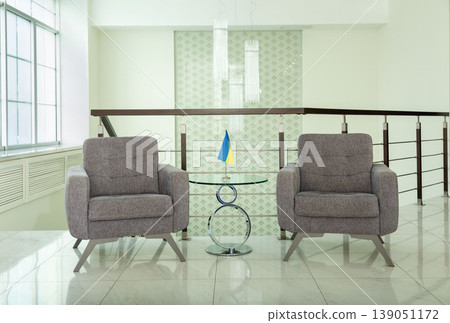 Modern armchairs and table with Ukrainian flag in office. Modern armchairs and table with Ukrainian flag in office. 139051172