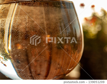 Macro of a glass of water with caustics and bubbles shot on the lumen. High-contrast backlighting highlights optical refraction, air spheres and liquid purity in a radiant clear composition 139051209