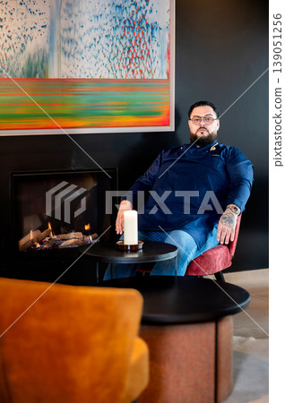 Chef by fireplace in modern dining, relaxed executive on break, warm candlelight and contemporary artwork create intimate atmosphere, velvet Chef by fireplace in modern dining, relaxed executive on break, warm candlelight and contemporary artwork create intimate atmosphere, velvet 139051256