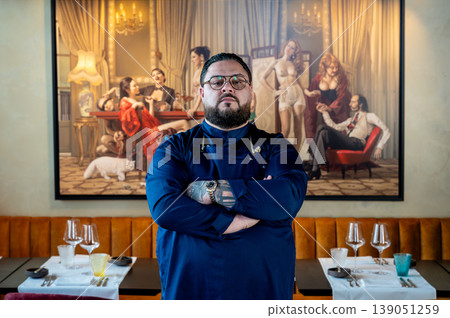 Chef in dining room, ready for service with set tables and glassware, confident posture signals leadership and preparation, classical Chef in dining room, ready for service with set tables and glassware, confident posture signals leadership and preparation, classical 139051259