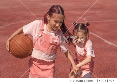 Children are fighting for a ball in a basketball game on a sports field. Naughty girls have fun together. 139051297