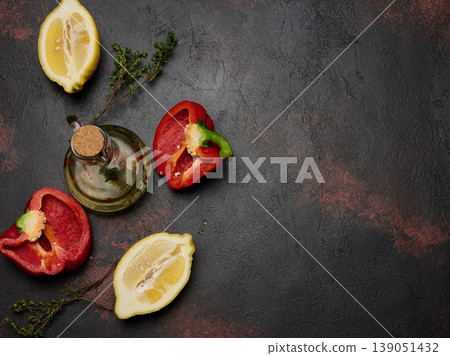 Red bell pepper halves, lemon, thyme sprigs, and a glass decanter of olive oil on a dark textured background. Red bell pepper halves, lemon, thyme sprigs, and a glass decanter of olive oil on a dark textured background. 139051432