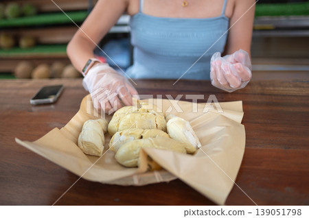 Woman Enjoying Fresh Durian at Local Market with Protective Gloves Woman Enjoying Fresh Durian at Local Market with Protective Gloves 139051798