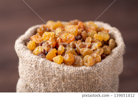 Small bag made of linen fiber full of raisins. Close up shot of sweet tasty raisins in bag Small bag made of linen fiber full of raisins. Close up shot of sweet tasty raisins in bag 139051812