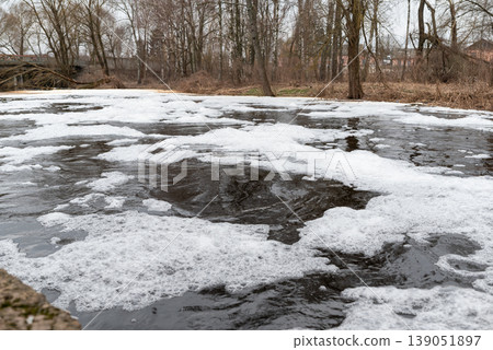 Foaming unclean water in a small river. Concept of pollution and water contamination, spring or autumn nature view on the background Foaming unclean water in a small river. Concept of pollution and water contamination, spring or autumn nature view on the background 139051897