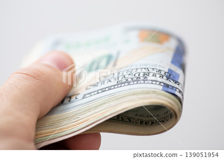 Thick pack of american 100 dollar banknotes in hand of a man, close up. Concept of richness, prosperity, expensive and luxury life Thick pack of american 100 dollar banknotes in hand of a man, close up. Concept of richness, prosperity, expensive and luxury life 139051954