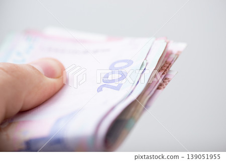Pack of 200 hryvnia bills in hand of a man, close up. Ukrainian paper money, wealth and cash money concept Pack of 200 hryvnia bills in hand of a man, close up. Ukrainian paper money, wealth and cash money concept 139051955