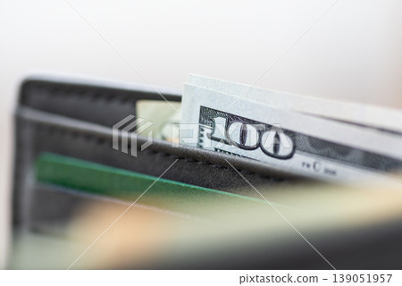 Grey wallet with money and credit cards, close up. Macro shot, focus on the edge of 100 american dollar banknote Grey wallet with money and credit cards, close up. Macro shot, focus on the edge of 100 american dollar banknote 139051957