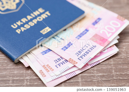 Biometric passport of ukrainian citizen with 200 hryvnias bills in it, close up. National currency concept, money and salary in Ukraine Biometric passport of ukrainian citizen with 200 hryvnias bills in it, close up. National currency concept, money and salary in Ukraine 139051963