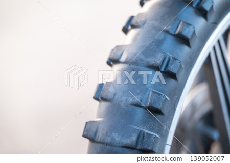 Worn tires on Enduro motorcycle, close up, copy space on the left. Care and renovation of the vehicle, speed, travel and enjoyment concepts Worn tires on Enduro motorcycle, close up, copy space on the left. Care and renovation of the vehicle, speed, travel and enjoyment concepts 139052007