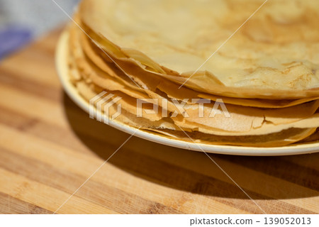 Close up of a tasty yellow crepes with crispy edges on a white plate. Concept of homemade food, sweets and dessert Close up of a tasty yellow crepes with crispy edges on a white plate. Concept of homemade food, sweets and dessert 139052013