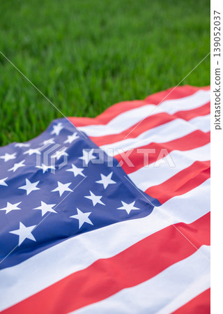American flag lays on the green wheat field, vertical shot, close up. Patriotic concept, United States of America independence day, national pride in the USA American flag lays on the green wheat field, vertical shot, close up. Patriotic concept, United States of America independence day, national pride in the USA 139052037