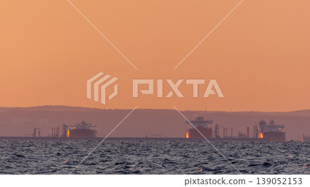 Oil tankers resting in calm sea during sunset 139052153