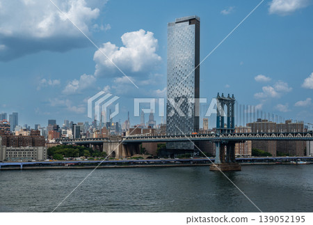 New york, usa august 15,2024. Manhattan bridge spanning the east river with one manhattan square and manhattan skyline towering over brooklyn waterfront, sunny day New york, usa august 15,2024. Manhattan bridge spanning the east river with one manhattan square and manhattan skyline towering over brooklyn waterfront, sunny day 139052195