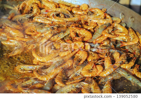 Shrimp cooking in large pan during outdoor picnic barbecue, seafood cooking scene, fresh shrimp frying in oil. Seafood cooking, outdoor food preparation, shrimp meal, street food cooking Shrimp cooking in large pan during outdoor picnic barbecue, seafood cooking scene, fresh shrimp frying in oil. Seafood cooking, outdoor food preparation, shrimp meal, street food cooking 139052580