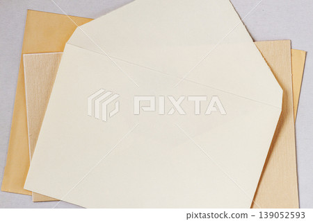 Envelope mockup with blank card placed over decorative paper sheets, minimal composition for stationery design, presentation, branding use. Envelope layout for invitation, mail, template, copy space 139052593