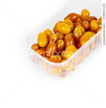 Plastic container of fresh yellow and orange cherry tomatoes isolated on white background. Tomatoes in transparent pack, perfect for grocery, retail, and food market visual content. Copy space 139053128