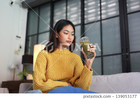 A woman enjoying green smoothie as part of a healthy lifestyle. A woman enjoying green smoothie as part of a healthy lifestyle. 139053177