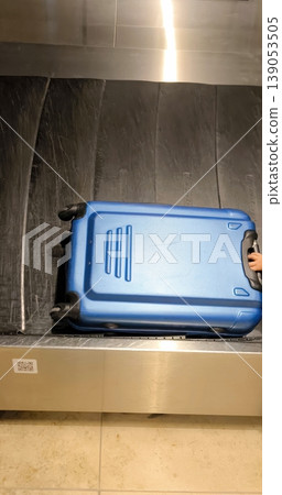 A blue suitcase moves along a baggage carousel at an airport A blue suitcase moves along a baggage carousel at an airport 139053505