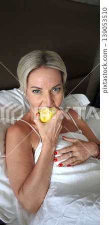 Morning in bed: woman enjoys fresh apple 139053510