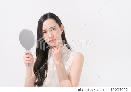 A woman looking in the mirror and troubled by skin problems. 139055032