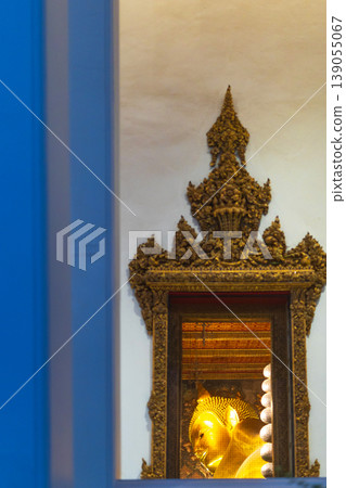 Golden Reclining Buddha statue illuminated within ornate temple architecture Golden Reclining Buddha statue illuminated within ornate temple architecture 139055067