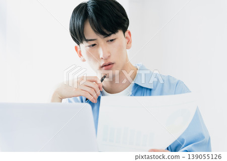 一位年輕人一邊看著文件一邊思考。 139055126