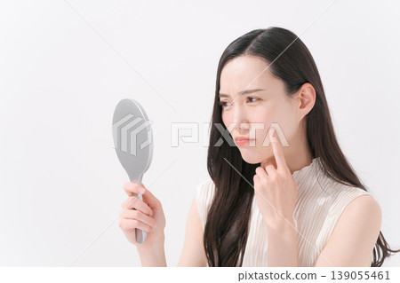 一位女士對著鏡子,為皮膚問題而煩惱。 一位女士對著鏡子,為皮膚問題而煩惱。 139055461