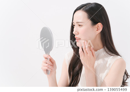 一個女人對著鏡子看著自己的嘴，感到擔憂 139055499