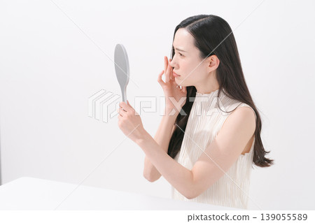 一位女士對著鏡子,為皮膚問題而煩惱。 一位女士對著鏡子,為皮膚問題而煩惱。 139055589