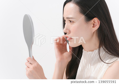 一位女士對著鏡子,為皮膚問題而煩惱。 一位女士對著鏡子,為皮膚問題而煩惱。 139055591