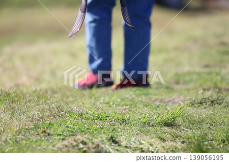 站在草地上,穿著紅色鞋子和牛仔布腳。 站在草地上,穿著紅色鞋子和牛仔布腳。 139056195